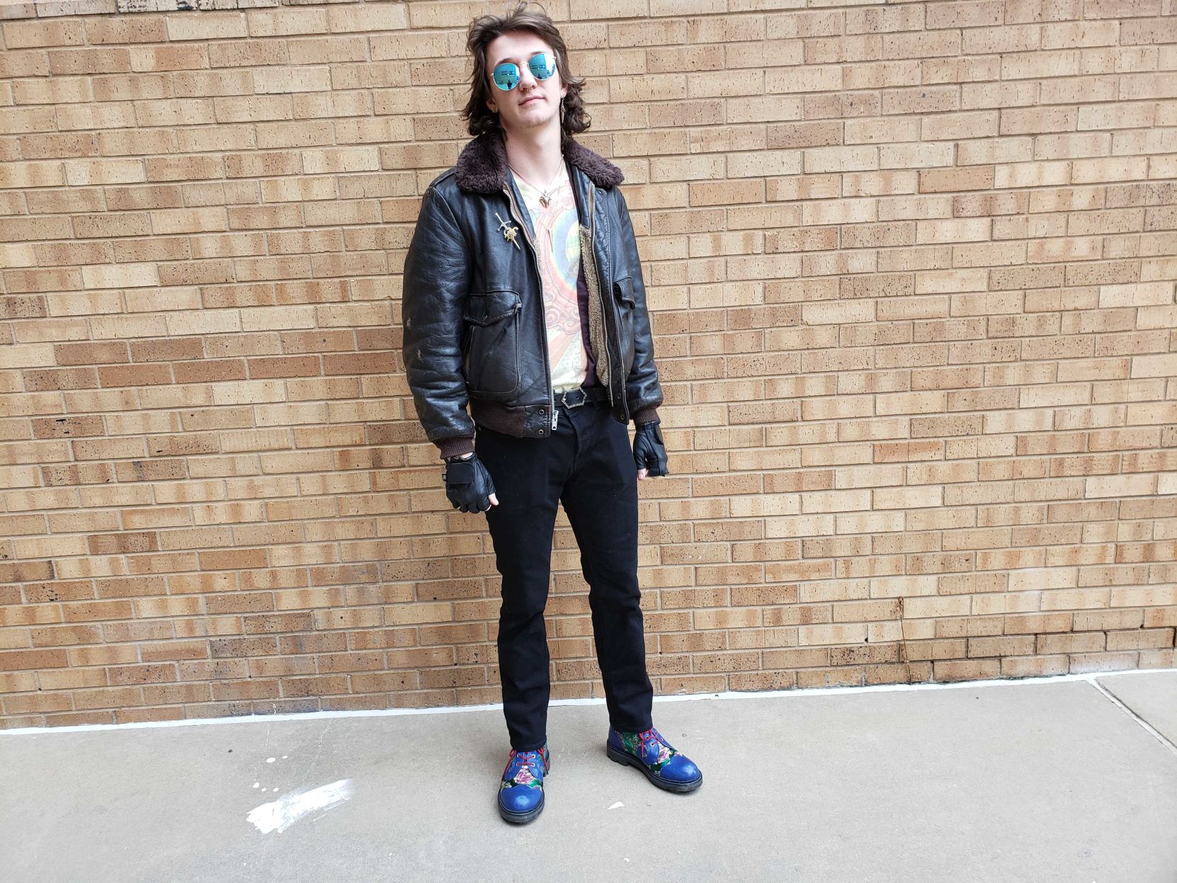 A man stands against a brick wall and looks at the camera